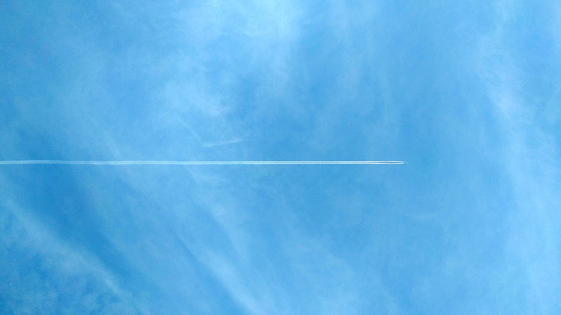 Plane vapour trail across a blue sky